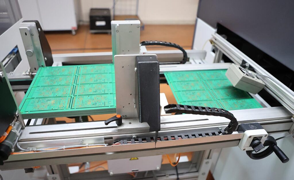 Ligne CMS automatisée de fabrication de cartes électroniques en série par pose et assemblage de composants : entrée du PCB dans la ligne de production